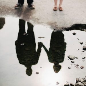 refection in a puddle of a couple holding hands