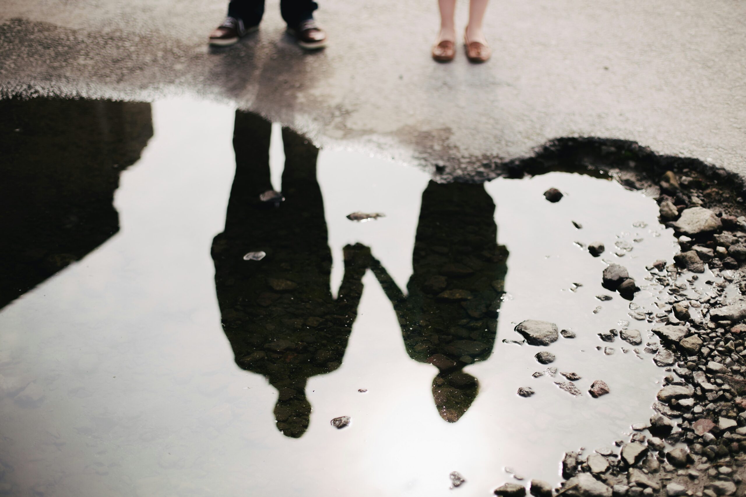 refection in a puddle of a couple holding hands