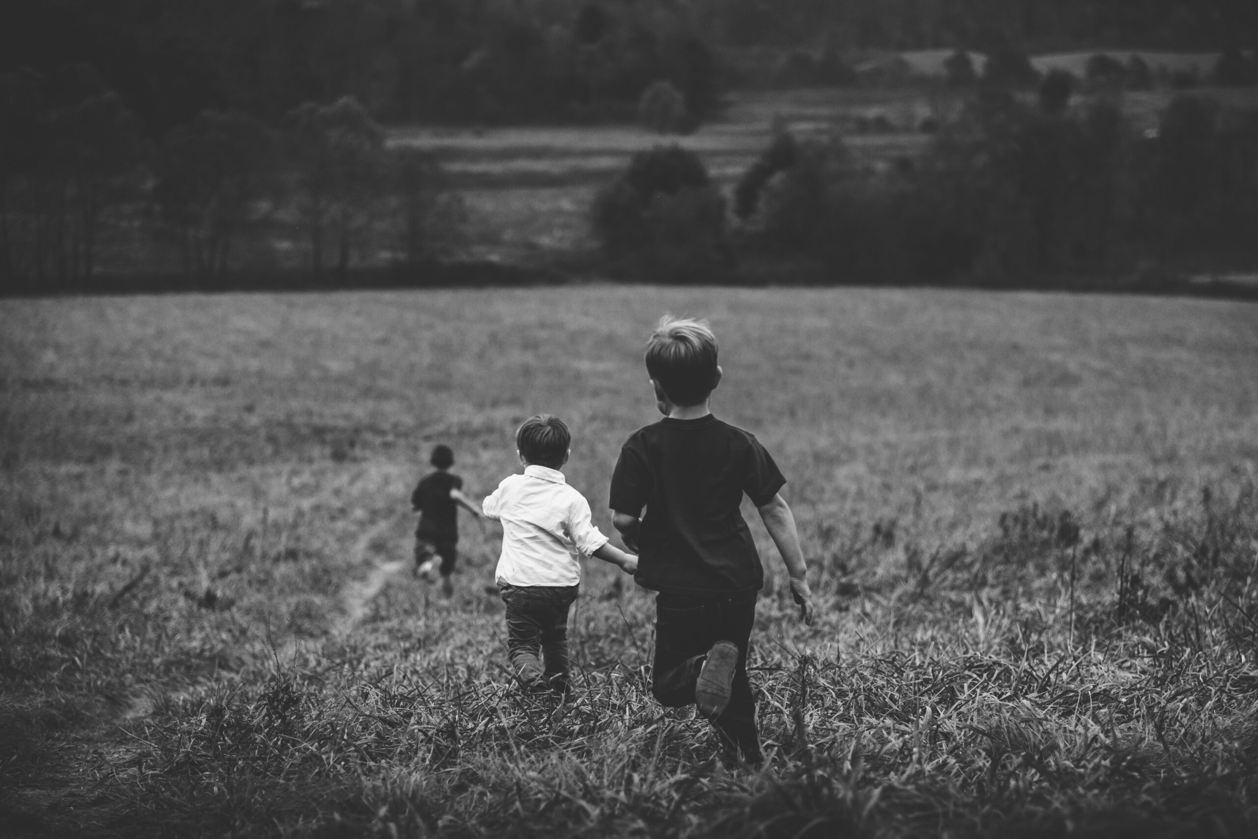 black and white image of children running through a field