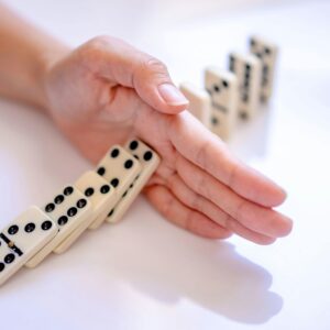 hand stopping dominoes from continuing to knock over, symbolising that Your Nervous System Is Not the Enemy and Understanding Reactions