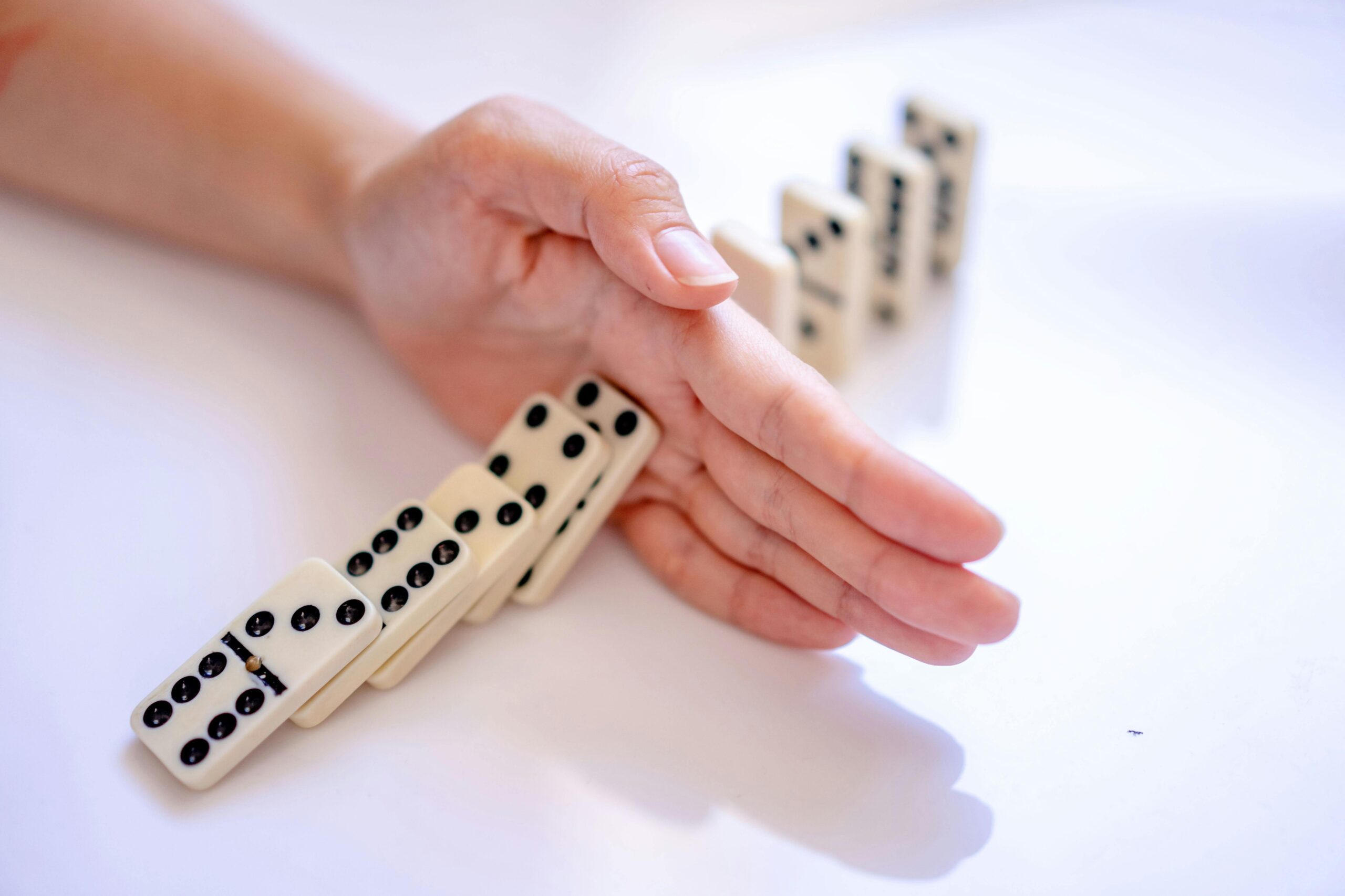 hand stopping dominoes from continuing to knock over, symbolising that Your Nervous System Is Not the Enemy and Understanding Reactions